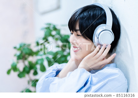 Young woman listening to music on headphones 85116316