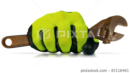 Extreme close-up of a hand with protective work glove, holding an old rusty adjustable wrench. Isolated on white background with reflections. 85116461