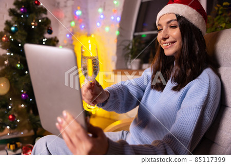 Emotional young girl using tablet, talking with friends by means of video calling. Christmas home decorations. Emotional young girl using tablet, talking with friends by means of video calling. Christmas home decorations. 85117399
