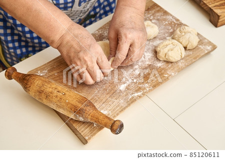 Mature woman makes basket of dough cooking pies in kitchen 85120611