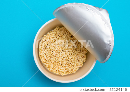Opened Package with Uncooked Instant Noodles on Blue Background 85124146