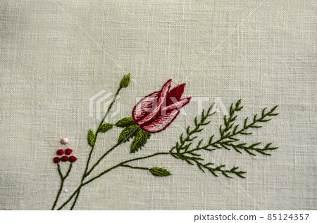 A twig with a red rose bud, a coniferous twig, red berries embroidered on a white cotton fabric. 85124357