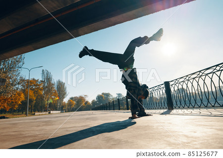 Young man break dancer dancing on urban background performing acrobatic stunts Young man break dancer dancing on urban background performing acrobatic stunts 85125677