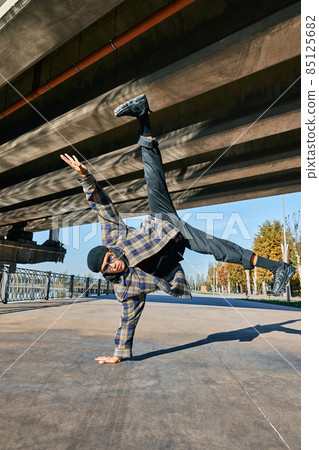 Young man break dancer dancing on urban background performing acrobatic stunts Young man break dancer dancing on urban background performing acrobatic stunts 85125682