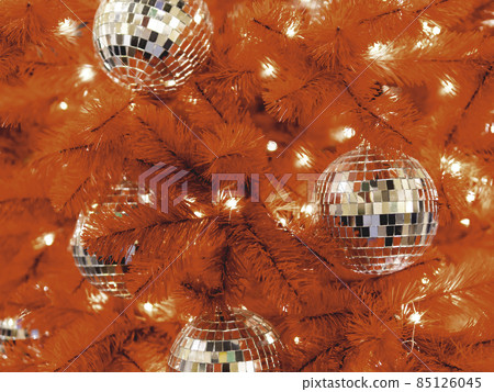 Red artificial Christmas tree with mirror disco balls. Bright fir tree decorated with light bulbs for New Year celebration. Red artificial Christmas tree with mirror disco balls. Bright fir tree decorated with light bulbs for New Year celebration. 85126045
