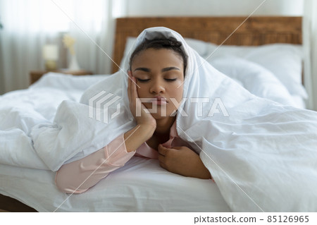 Sleepless night, problems and insomnia. Young african american lady with closed eyes lying under blanket on bed 85126965
