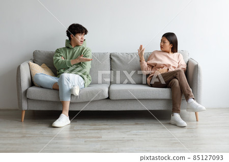 Breakup and divorce concept. Young married Asian couple having fight, sitting on opposite sides of couch at home 85127093