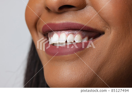 Close-up female beautiful lips, mouth and white straight teeth isolated on gray studio background. Natural beauty Close-up female beautiful lips, mouth and white straight teeth isolated on gray studio background. Natural beauty 85127494