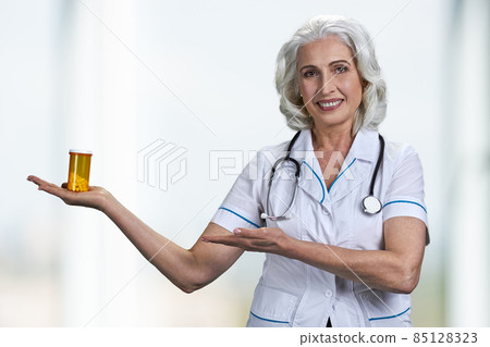 Happy mature woman doctor showing bottle of pills. 85128323