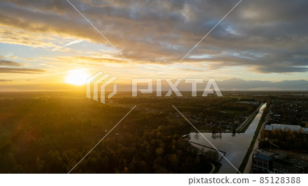 Beautiful sunset over a river with green bushes and color rich sky Beautiful sunset over a river with green bushes and color rich sky 85128388