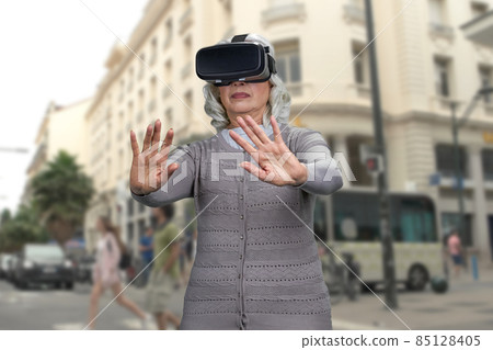 Old lady shocked experiencing virtual reality headset. 85128405