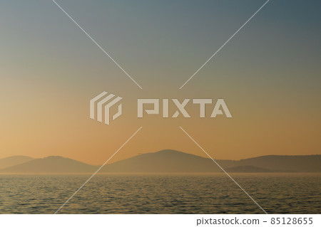 Hazy sunset seascape with sea horizon and clear sky, with mountain islands, natural photo background. 85128655