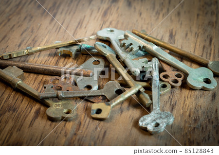Old keys stacked on a wood board 85128843