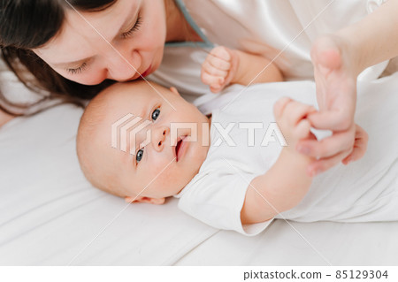 mom lies with the baby in bed. the happiness of motherhood. mom lies with the baby in bed. the happiness of motherhood. 85129304