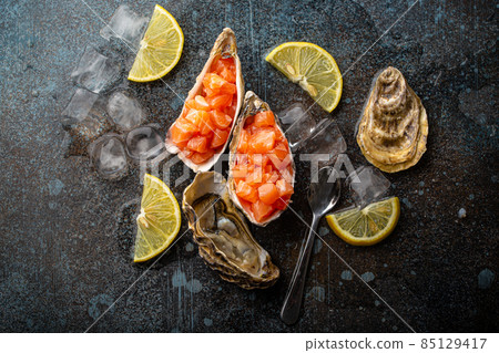 Salmon tartare raw chopped served in oyster shells top view on stone background Salmon tartare raw chopped served in oyster shells top view on stone background 85129417