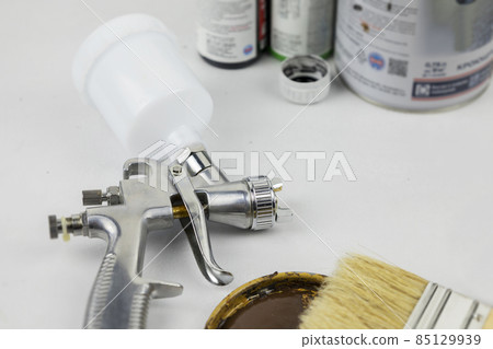 Instructions and a paint spray gun at work at the workplace in the workshop. 85129939