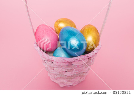 Multi-colored Easter eggs in a basket on a pink isolated background. Easter is a bright holiday. Multi-colored Easter eggs in a basket on a pink isolated background. Easter is a bright holiday. 85130831
