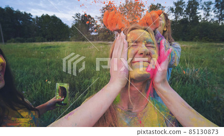 Funny girls are sprinkled with multi-colored powder. Holi holiday. Funny girls are sprinkled with multi-colored powder. Holi holiday. 85130873