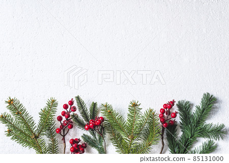 Chrismtas holiday background: frame of fir branches and holly berry twigs on white background; copy space 85131000