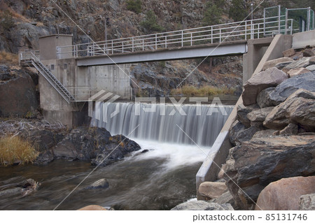 diversion dam on a mountain river flowing in deep, dark canyon 85131746