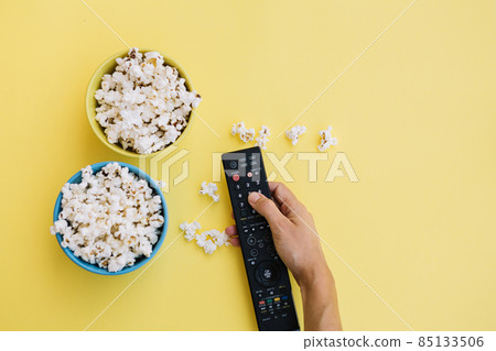 crop hand remote control near popcorn. High quality photo crop hand remote control near popcorn. High quality photo 85133506