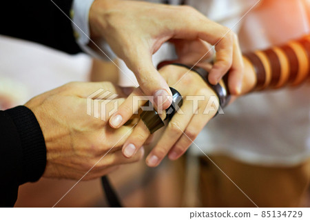 Detail of a moment when a Jewish rabbi puts tefillin on the arm of a thirteen year old boy to say a prayer before the bar mitzvah Detail of a moment when a Jewish rabbi puts tefillin on the arm of a thirteen year old boy to say a prayer before the bar mitzvah 85134729