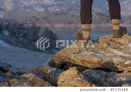 hiker or trail runner legs on rock overlooking mountain lake 85135389