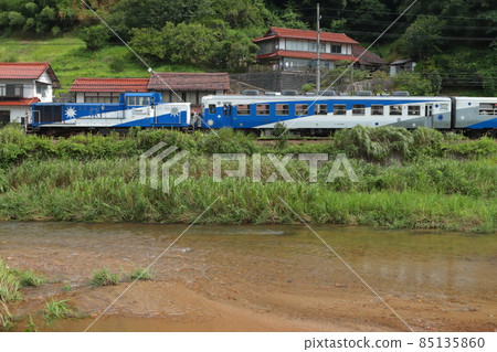 The DE15-propelled Okuizumo Orochi train runs leisurely through houses made of the famous Sekishu tile roofing. Photographed on August 11, 2021 85135860