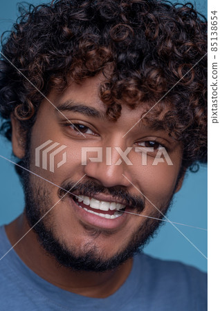 Pleased cute young man using dental floss Pleased cute young man using dental floss 85138654