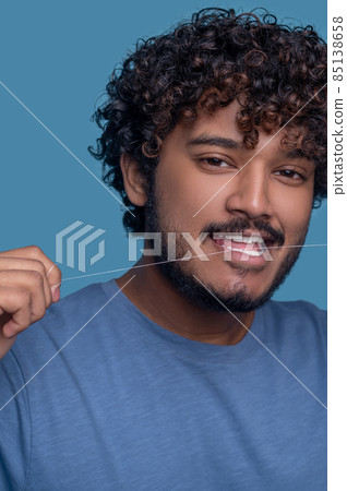 Serene Indian guy using the tooth floss Serene Indian guy using the tooth floss 85138658