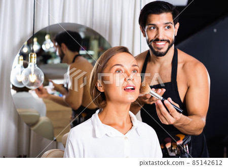 Man makeup artist applying cosmetics for woman Man makeup artist applying cosmetics for woman 85142612