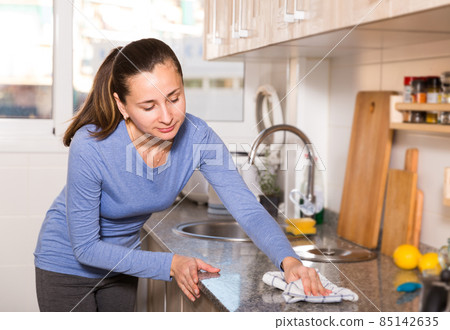 Smiling woman is cleaning surface on the kitchen at the home Smiling woman is cleaning surface on the kitchen at the home 85142635