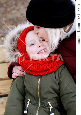 Young mother talking to her cute little daughter outdoors sitting together Young mother talking to her cute little daughter outdoors sitting together 85145504