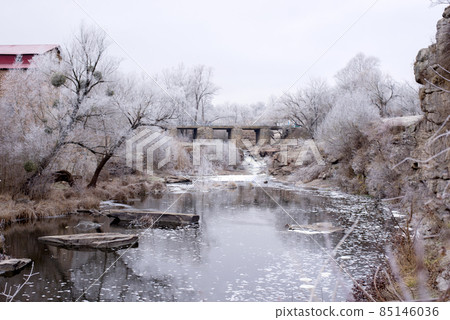Beautiful winter landscape with Old stone bridge across the Girskiy Tikych river running through frosted trees and rocks. Beautiful winter landscape with Old stone bridge across the Girskiy Tikych river running through frosted trees and rocks. 85146036