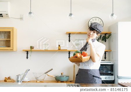 A cook wearing a cook coat standing in the kitchen (vegetables, troubled) A cook wearing a cook coat standing in the kitchen (vegetables, troubled) 85146175
