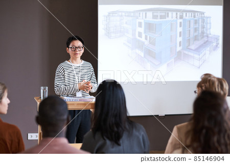 Asian businesswoman in eyeglasses presenting her report for people at the seminar, she talking about the blueprint of modern building 85146904