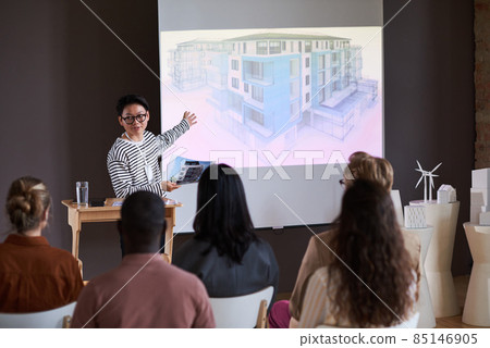 Asian young man in eyeglasses pointing at whiteboard with modern building and explaining the blueprint for business people at seminar 85146905