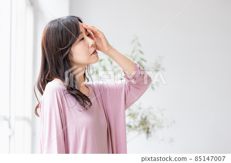 一個生病的女人，在房間裡把手放在額頭上 85147007