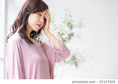 A sick woman who puts her hand on her forehead in the room A sick woman who puts her hand on her forehead in the room 85147008