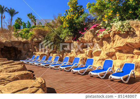 Several of sun loungers by a beautiful swimming pool. Several of sun loungers by a beautiful swimming pool. 85148007