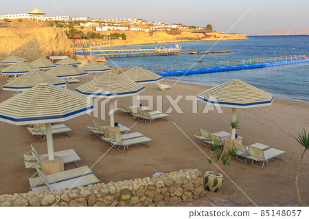 Beach with deck chairs and parasol during sunset Beach with deck chairs and parasol during sunset 85148057