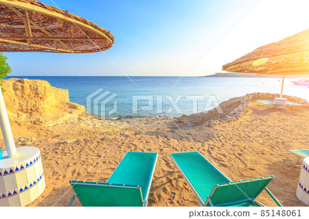 Sun umbrellas and empty deckchairs on the shore sand beach Sun umbrellas and empty deckchairs on the shore sand beach 85148061
