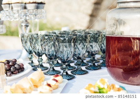 Elegant blue glasses without champagne stand in row next to canapes and snacks on picturesque background. 85148151