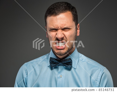Portrait angry upset young man in blue shirt, butterfly tie 85148731