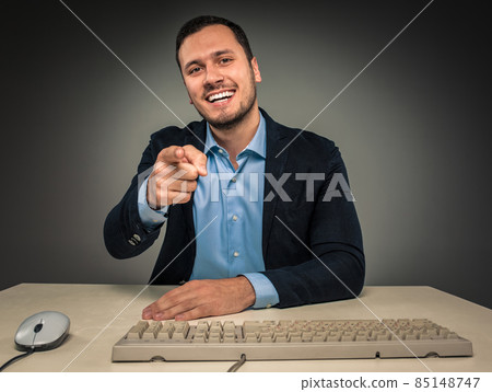 Smiling man is gesturing with hand, pointing finger at camera Smiling man is gesturing with hand, pointing finger at camera 85148747