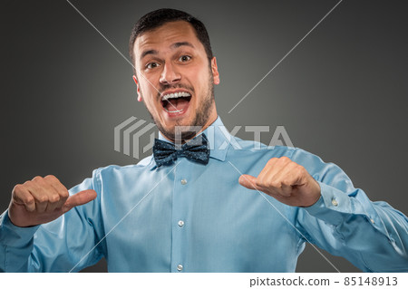 Smiling man is gesturing with hand, pointing finger shows itself Smiling man is gesturing with hand, pointing finger shows itself 85148913