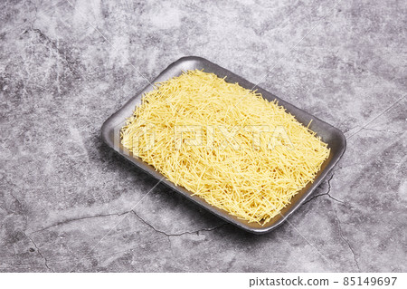 Black tray full of raw noodles on a gray stone background. Pasta, Italian food Black tray full of raw noodles on a gray stone background. Pasta, Italian food 85149697