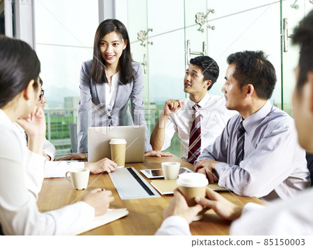 young asian businesswoman speaking to teammates during meeting in modern office 85150003