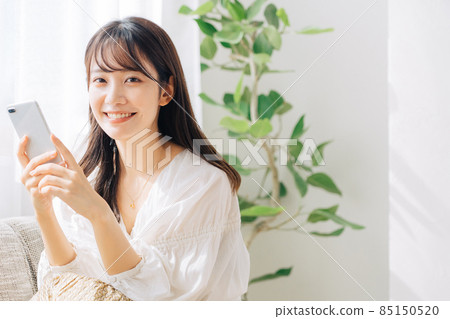 一個女人坐在沙發上使用智能手機 85150520