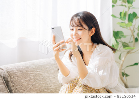 坐沙發和看智能手機的婦女 坐沙發和看智能手機的婦女 85150534
